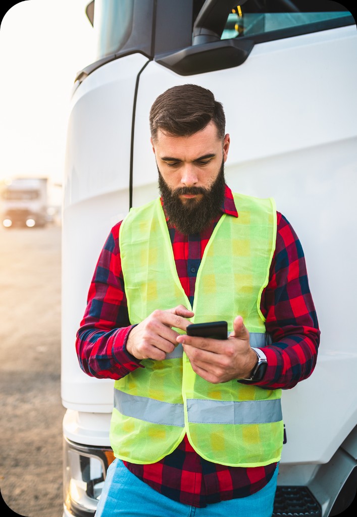Driver reviewing a new route on their phone beside a delivery truck